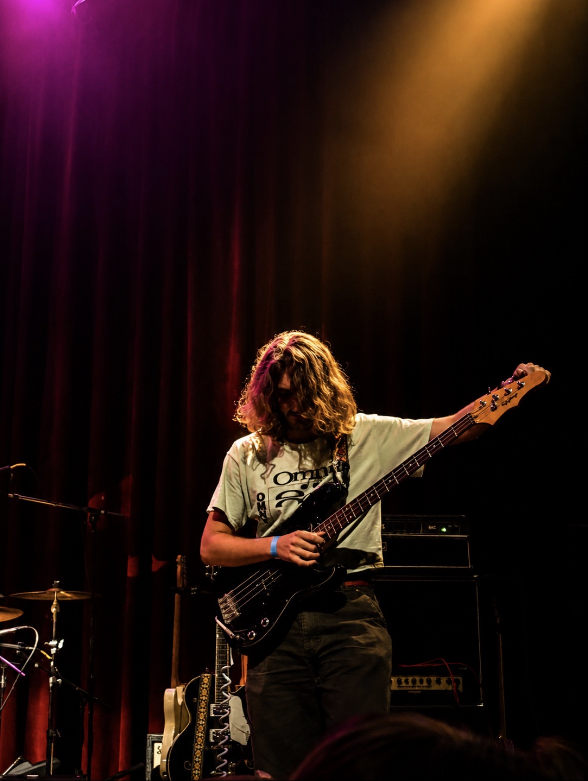 Bass player tuning under orange and purple spotlights