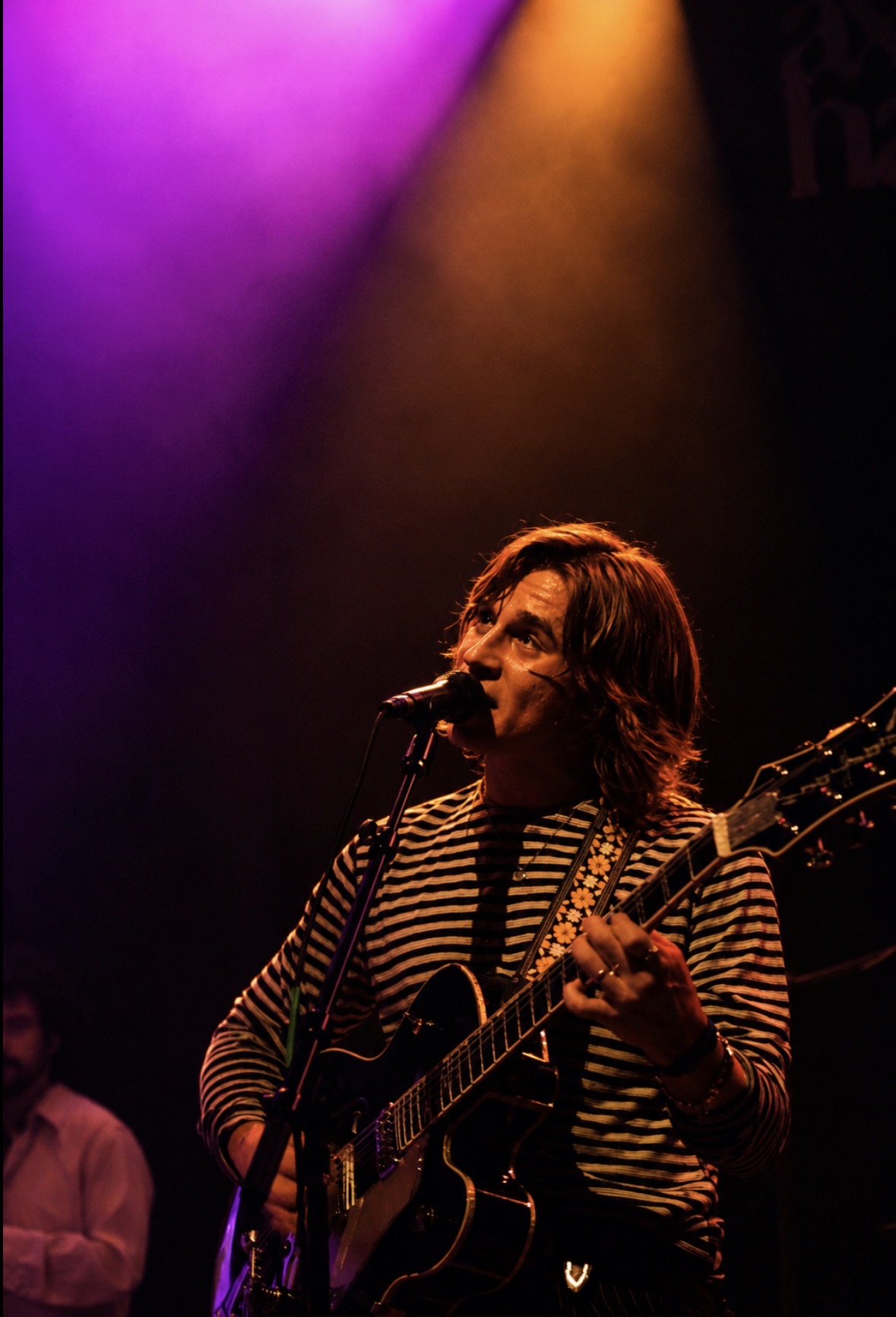 Singer and guitarist under purple and amber stage lights