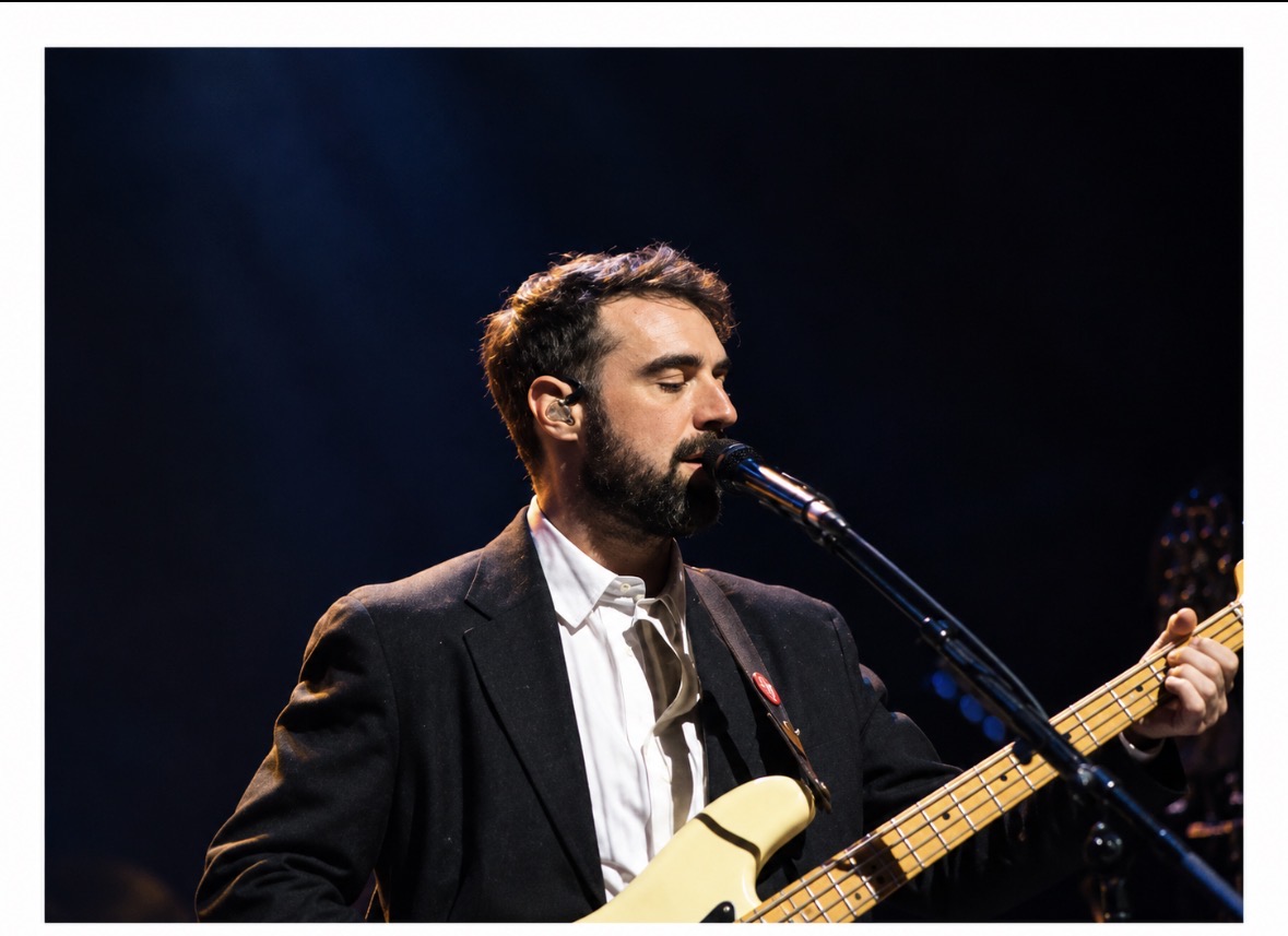 Bassist singing under dark blue stage lighting