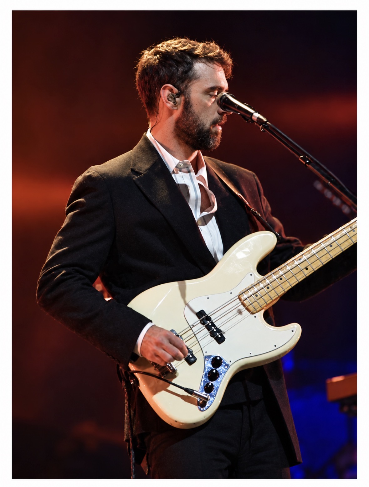 Bassist performing at the microphone under warm stage lights